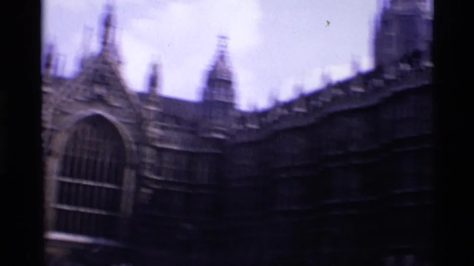 1969 London 8mm frame with a soft, handheld view of Gothic stone architecture, an arched window, and upper roofline details.