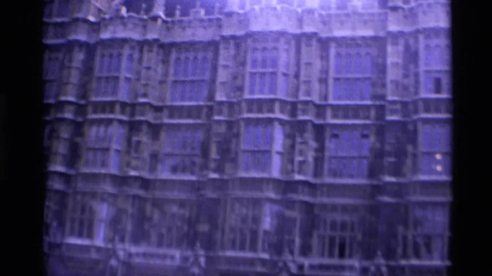 1969 London home-movie frame showing a large Gothic-style church facade with traceried windows and dark film edges.