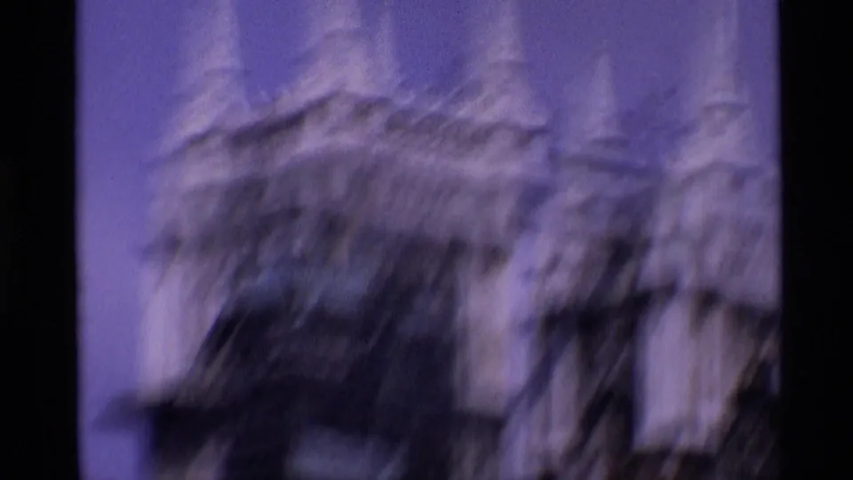1969 London 8mm frame with motion-blurred Gothic stone ornament and vertical architectural forms during an upward camera move.