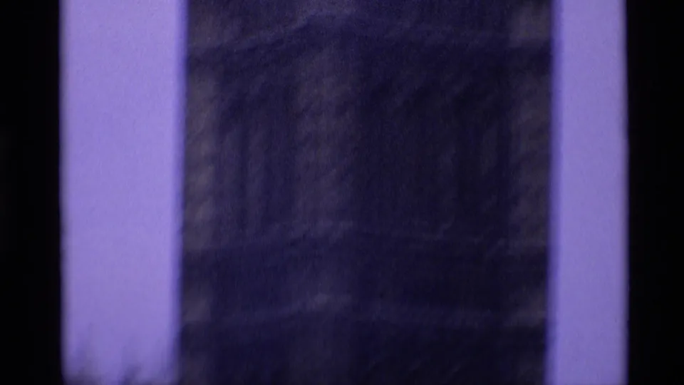 1969 8mm frame with mostly dark blurred content, pale vertical edges, and minimal architectural detail visible.