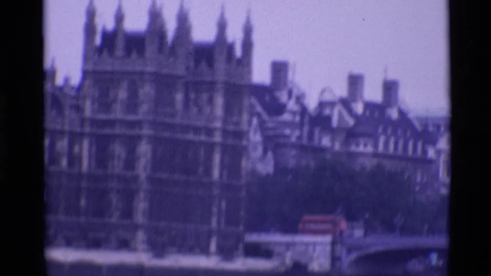 1969 London 8mm frame showing the Palace of Westminster, Thames-side bridge structure, and a red double-decker bus.