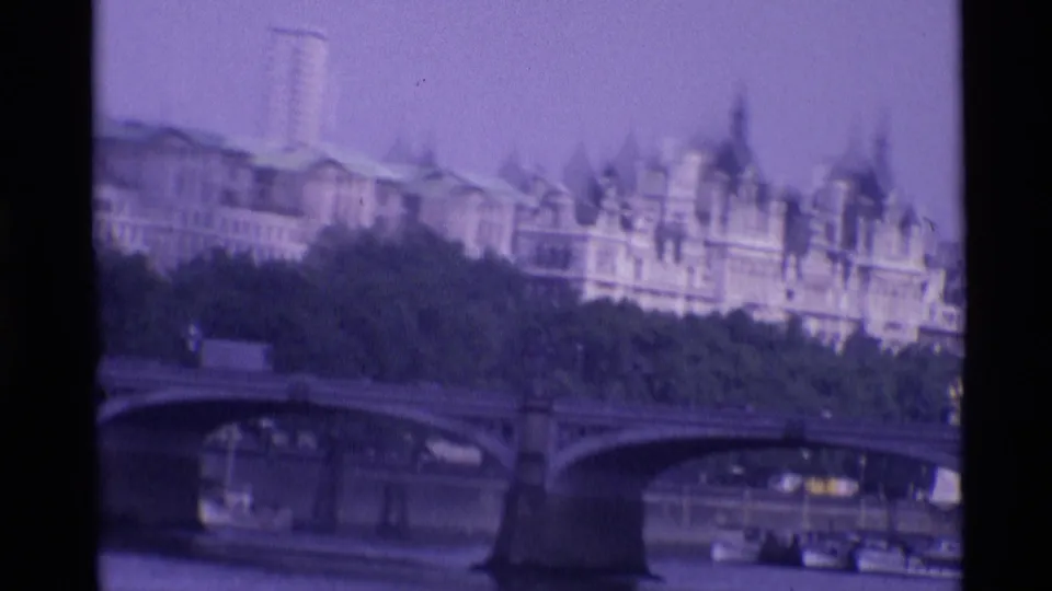 1969 London 8mm frame with Westminster Bridge in the foreground and Palace of Westminster buildings beyond trees.
