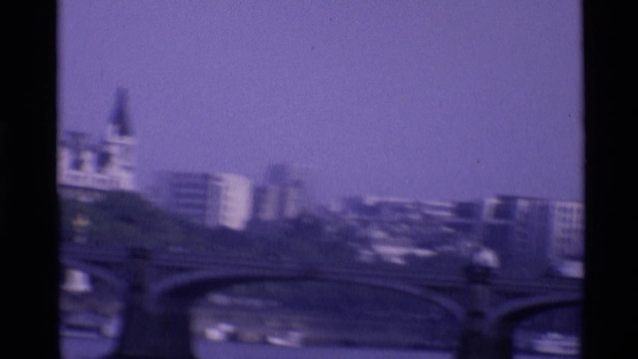 Soft 1969 London view across the Thames, with bridge arches, traffic, boats, and modern riverside buildings.