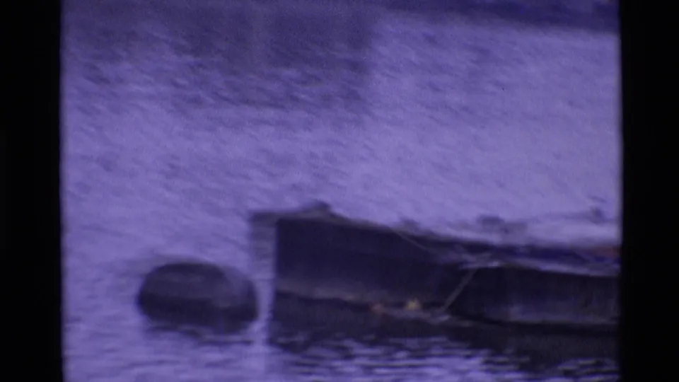 Small boats float on water in a soft, purple-shifted 1969 London home-movie frame.