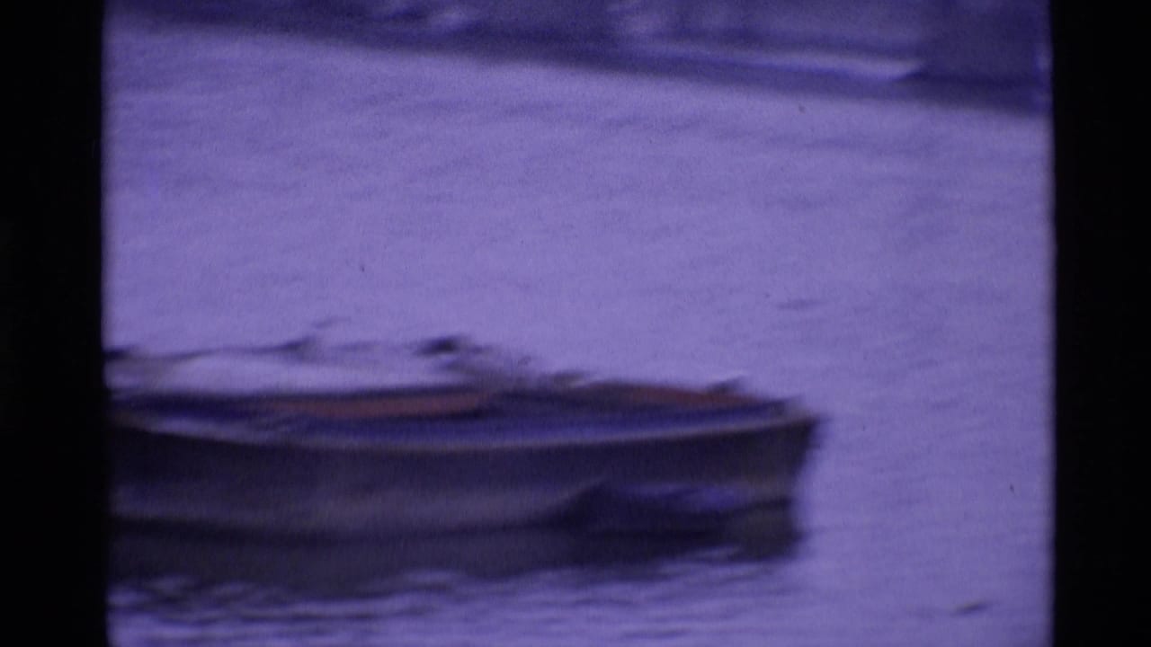 A small boat sits on London water in a purple-shifted 8mm frame with visible film borders.
