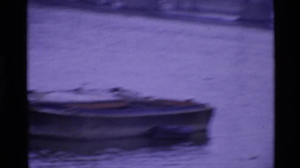 A small boat sits on London water in a purple-shifted 8mm frame with visible film borders.