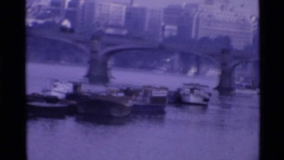A ceremonial guard appears near railings in 1969 London, with bridge arches and small boats in the background.