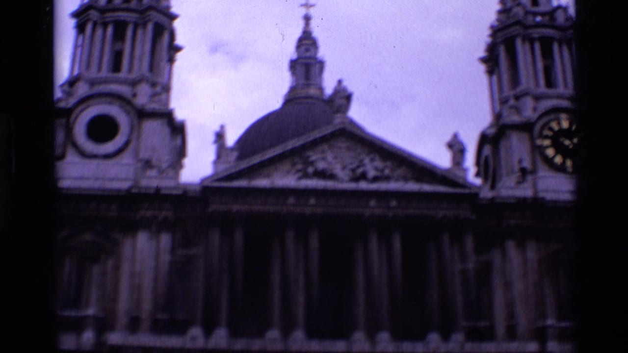 Classical stone building with twin towers, dome, columns, and a clock face under an overcast sky.