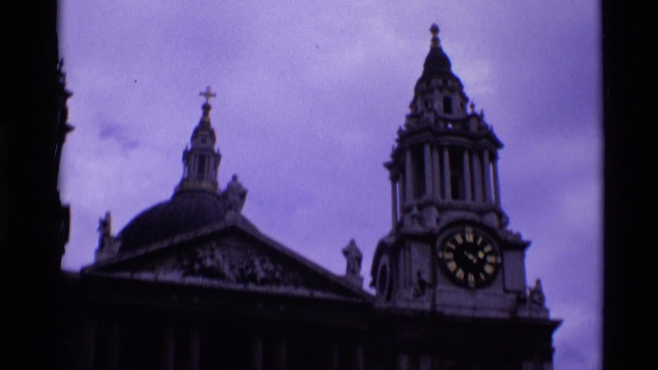 1969 London home-movie frame showing the right portion of a classical church-like facade with a clock tower and domed roofline.