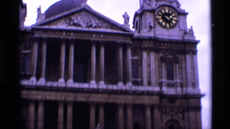1969 London 8mm frame showing a closer visitor view of a columned stone facade with pediment detail and clock face.