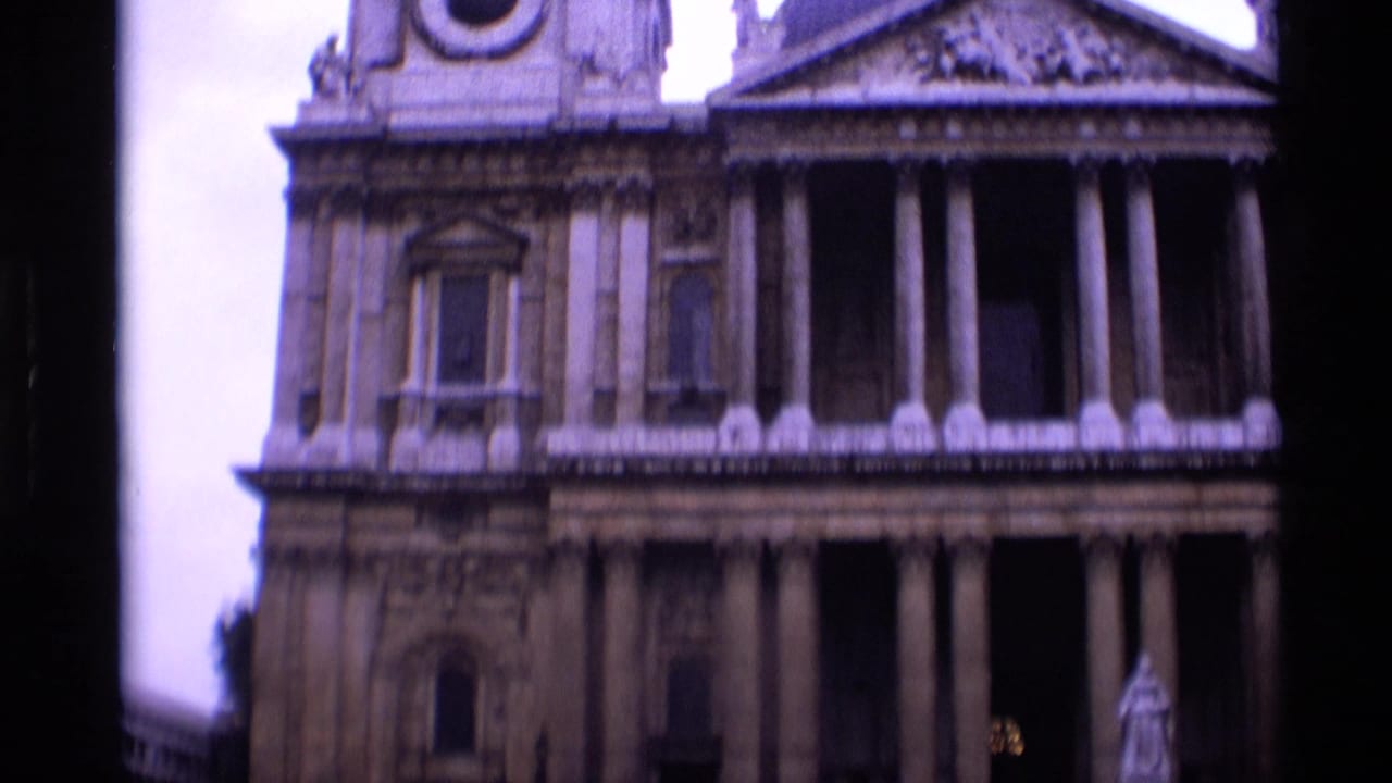 1969 London church exterior with a stone facade, tall columns, a dome, and a triangular pediment seen in soft 8mm focus.