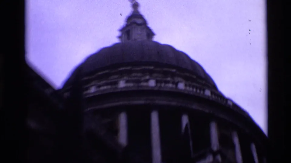 Low-angle 1969 London view of St Paul's Cathedral's dome, columned drum, and small lantern in purple-shifted 8mm film.