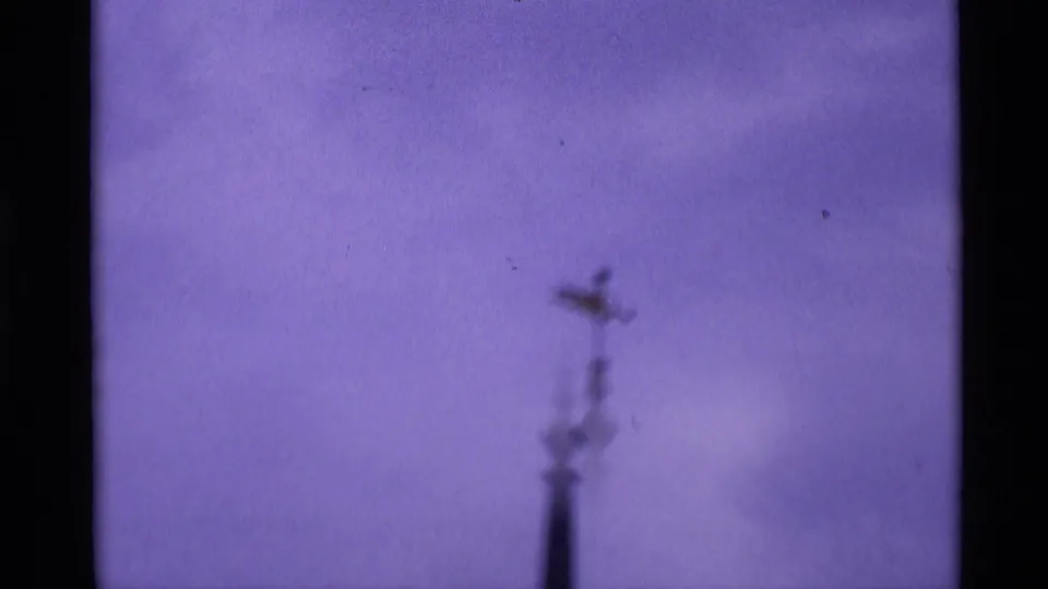 Soft 8mm frame from the St Paul's Cathedral sequence showing a blurred cross-topped architectural detail against the sky.