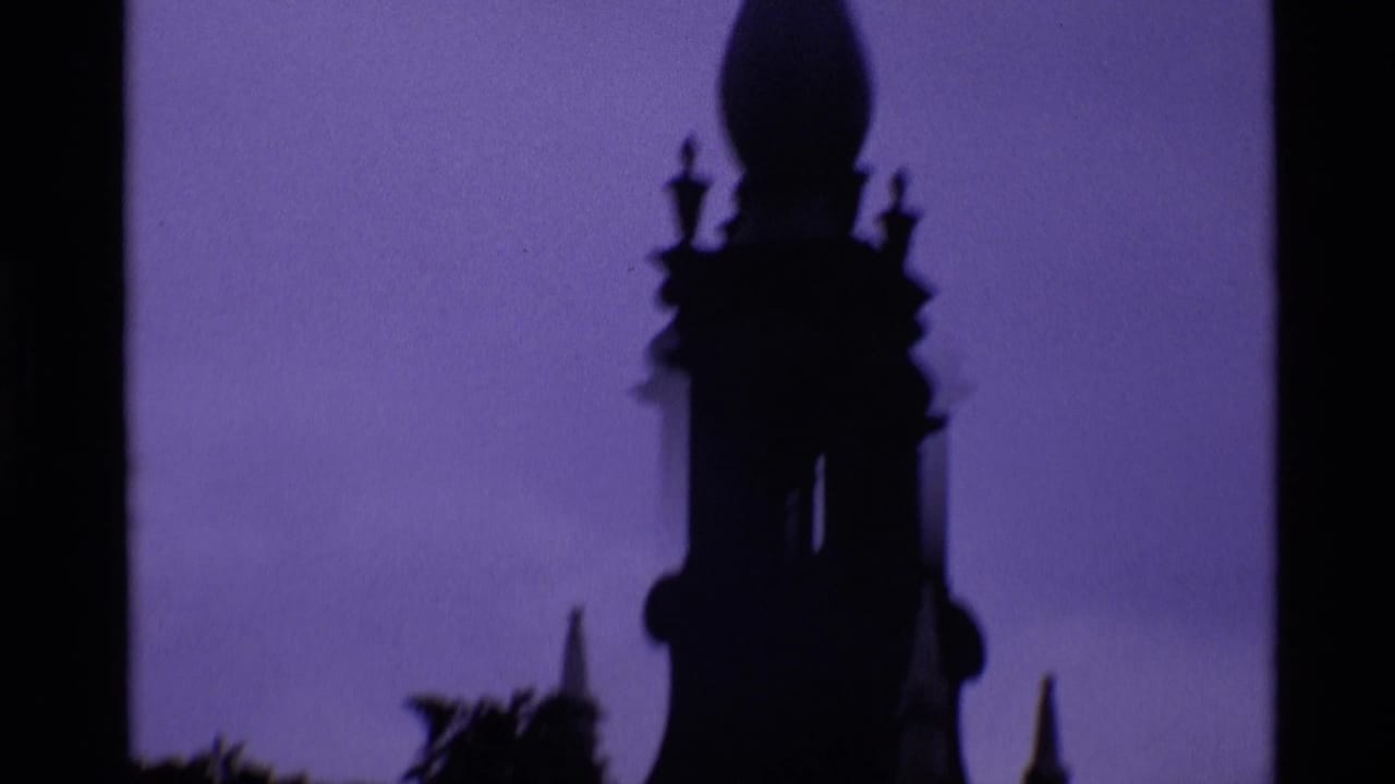 1969 London 8mm frame showing a tall church steeple in silhouette, with soft focus and purple-blue color fading.