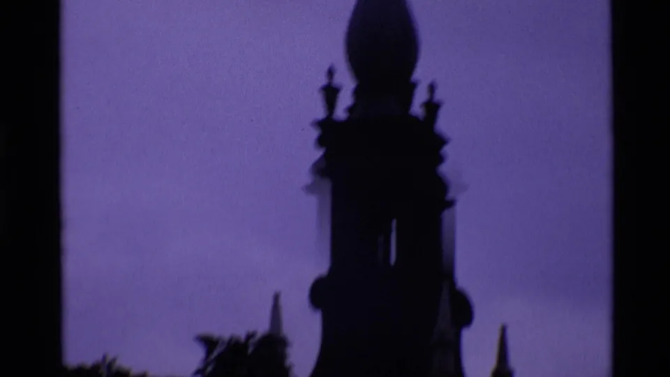 1969 London 8mm frame showing a tall church steeple in silhouette, with soft focus and purple-blue color fading.