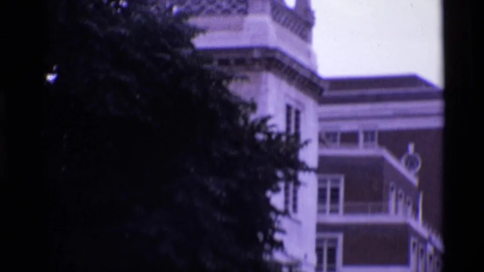 London exterior view with an ornate upper facade and nearby trees, captured in soft, faded 8mm color.