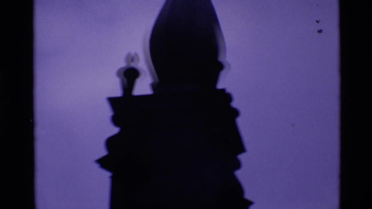 Dark spire silhouette against a purple-tinted sky with film edges visible.