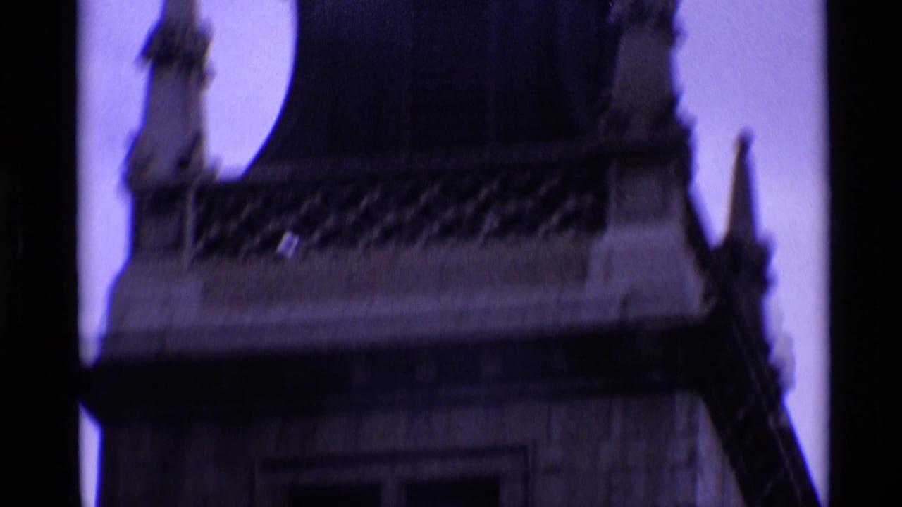 Upper stone tower with ornate roofline and dark vertical frame edge.