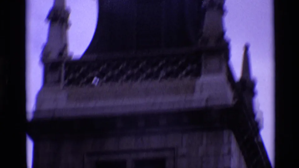 1969 London 8mm view of an upper stone tower section with decorative roofline and dark film-edge framing.
