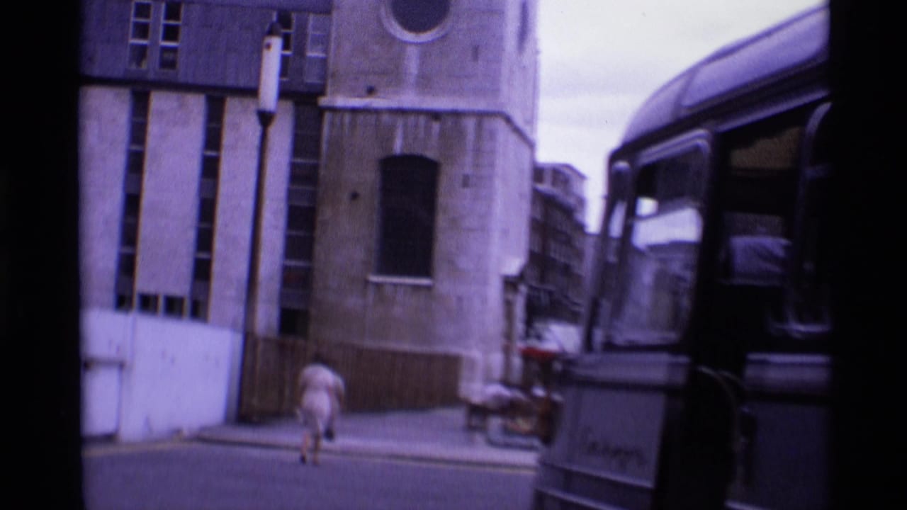 Street beside stone buildings with a pedestrian, a classic bus, and architectural details.