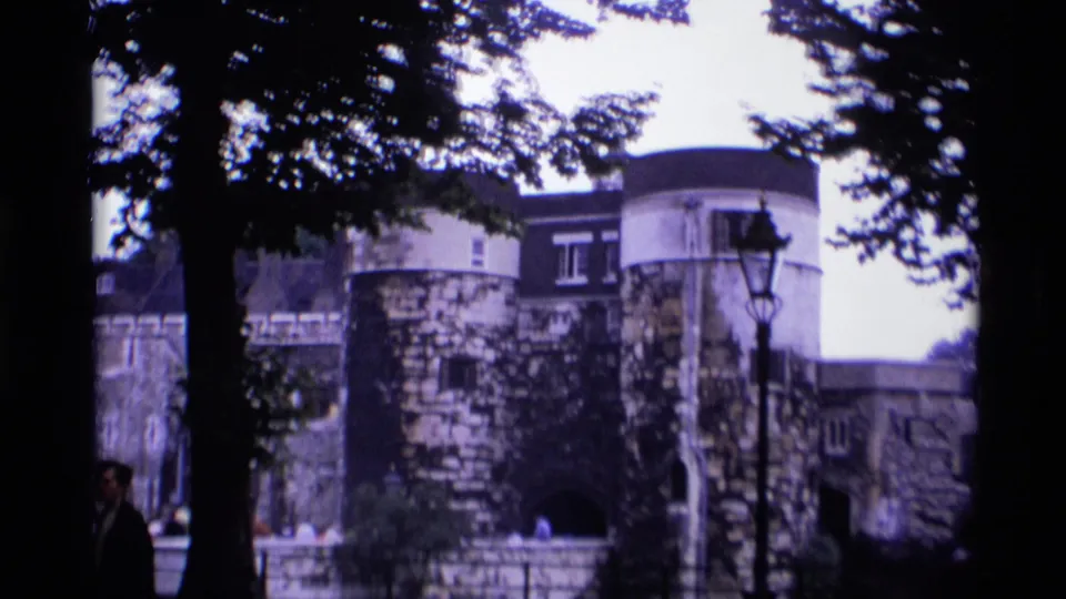 1969 London home-movie view of a historic stone wall, arched opening, trees, and a lamppost.