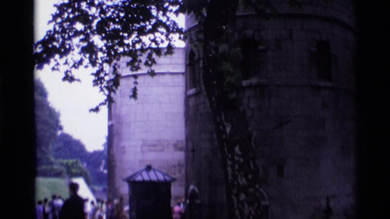 Tourists near a stone tower and small kiosk at a historic London fortress.