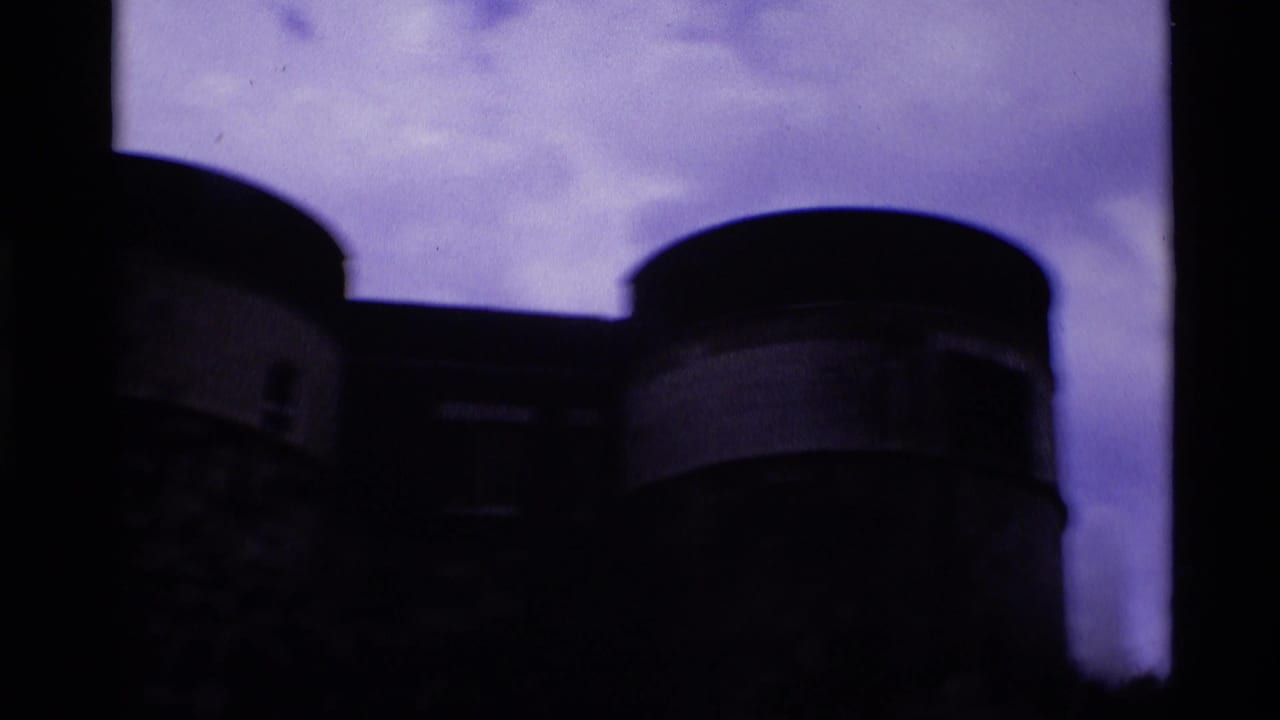 Dark silhouetted round towers and fortress walls against a cloudy sky.