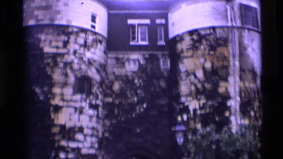 1969 home-movie frame of round stone towers at the Tower of London, with masonry, windows, and a building visible behind.