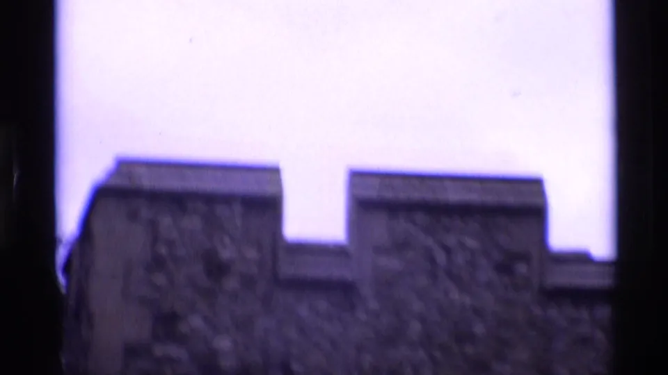 Soft 1969 8mm view of stone battlements at a London fortress, framed low against a bright purple-tinted sky.