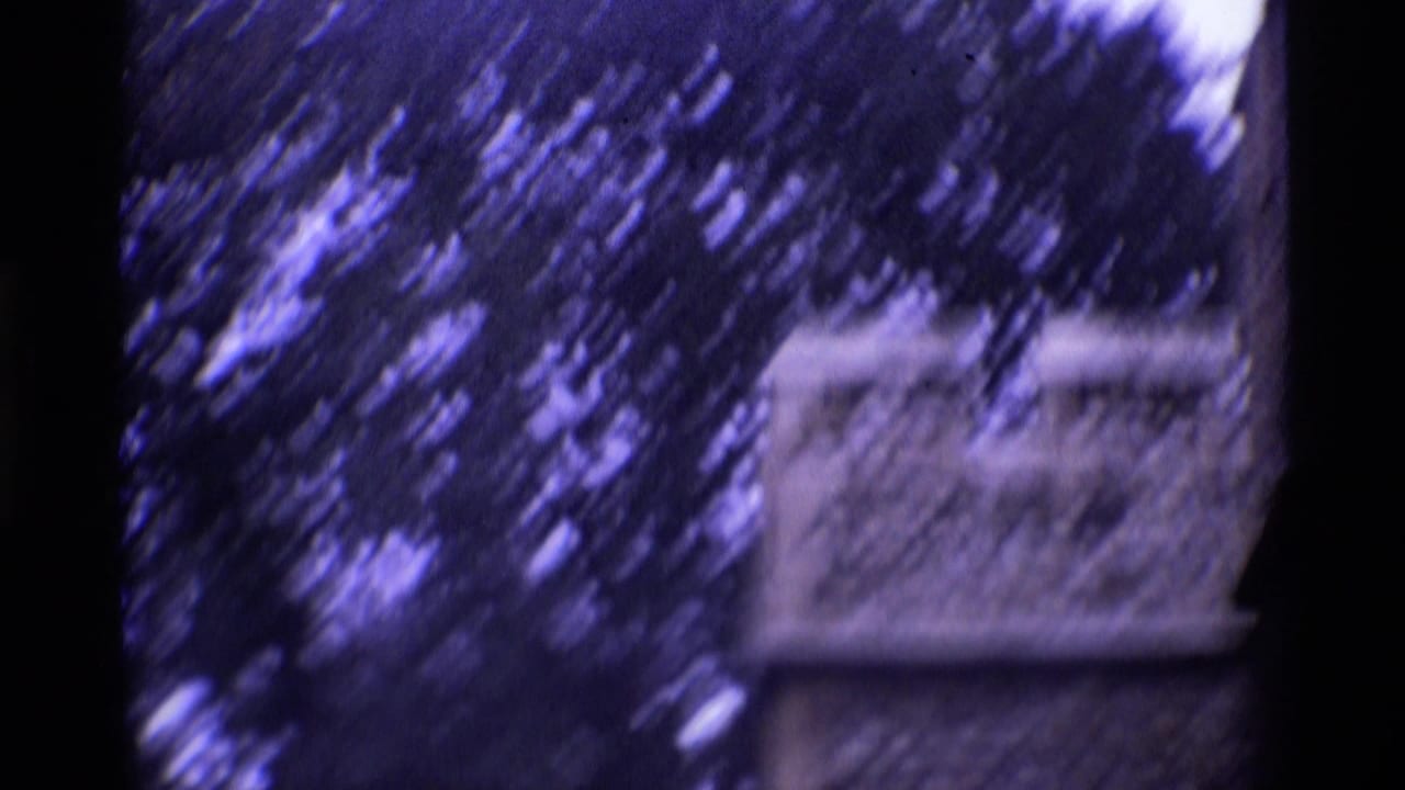 1969 London 8mm frame showing crenellated stonework and trees in a blurred handheld view.