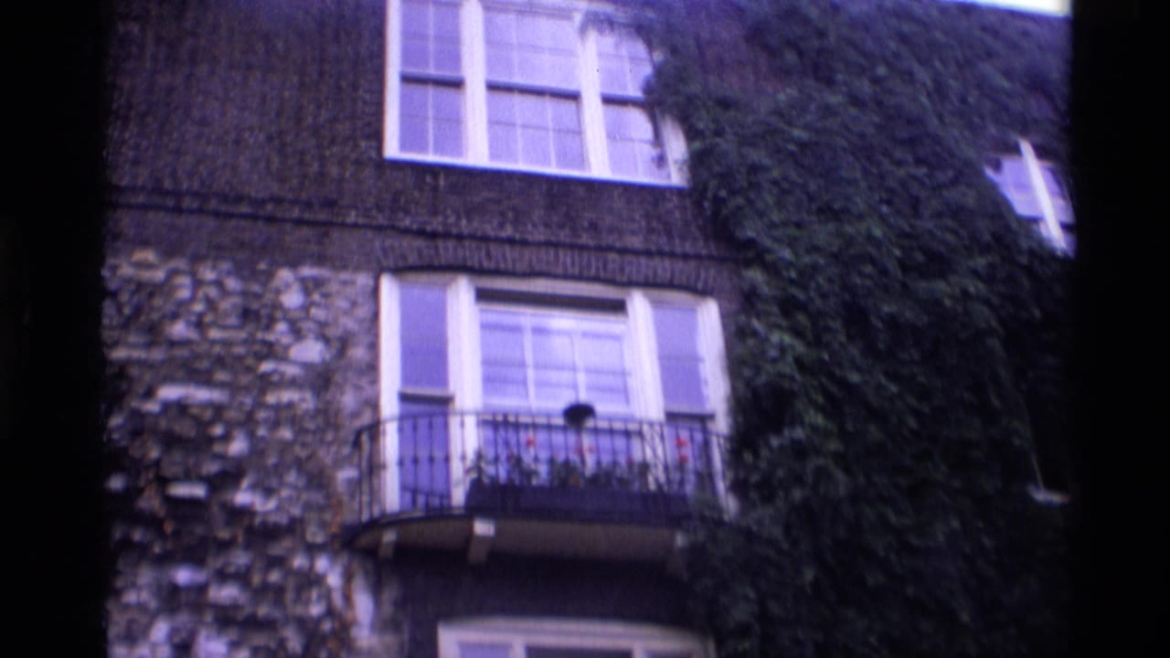 1969 London exterior with ivy-covered stonework, large windows, and a small balcony with flowers.