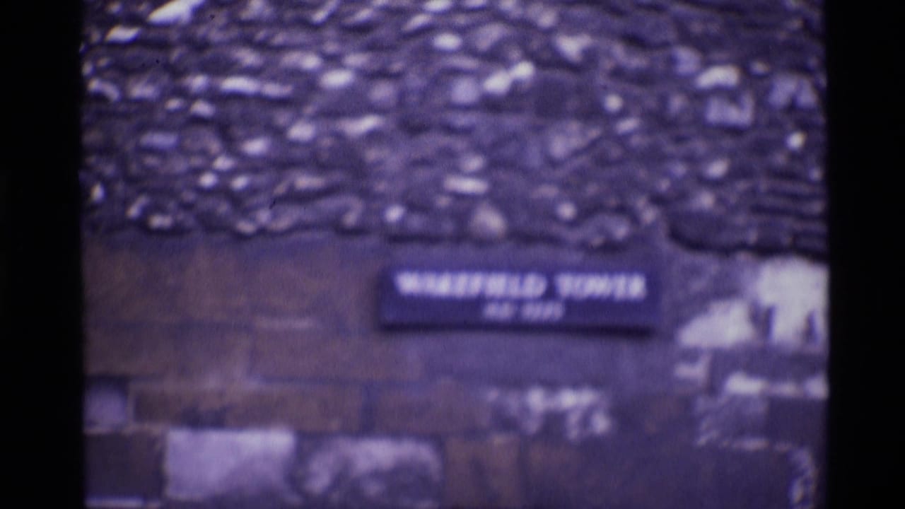 1969 London home-movie frame showing a blurred Wakefield Tower plaque set into rough stonework.