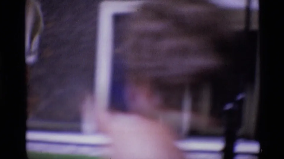 Blurred 1969 London home-movie frame with a close foreground figure and indistinct building details behind.