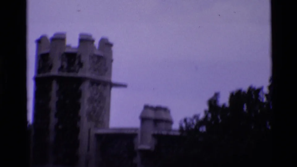 1969 London home-movie frame showing a Tower of London stone tower in soft focus with dark film-edge or foreground obstruction.