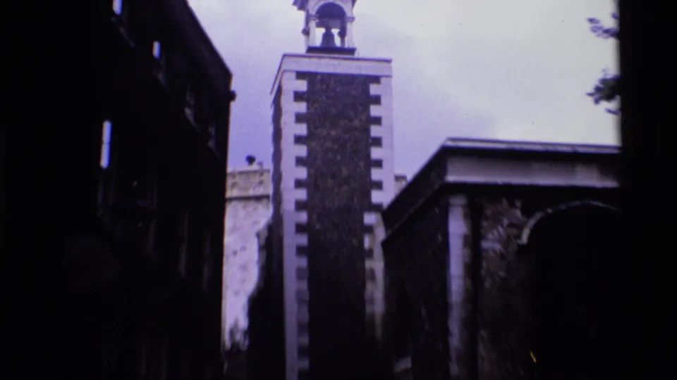 1969 London 8mm frame tilting down to show the brick tower, adjacent buildings, and an arched passage below.