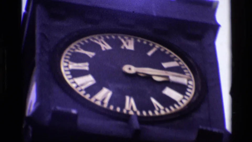 1969 London 8mm frame showing a close-up of the tower clock face with Roman numerals and clock hands.