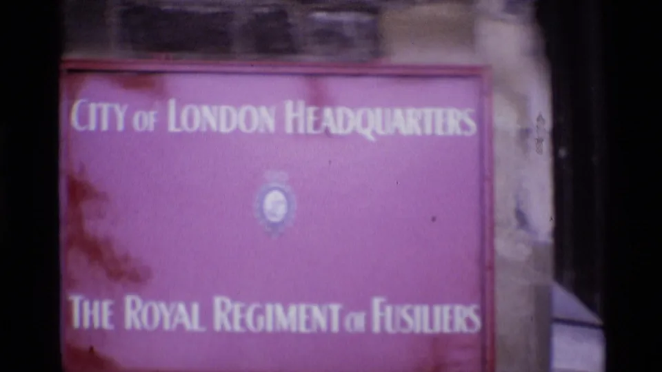 1969 London 8mm frame showing a purple City of London Headquarters sign for The Royal Regiment of Fusiliers mounted on stonework.