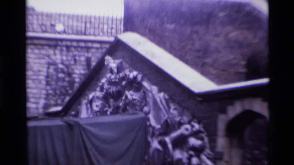 1969 London 8mm frame showing a stone exterior, railings, and a covered monument or decorative structure near the headquarters frontage.