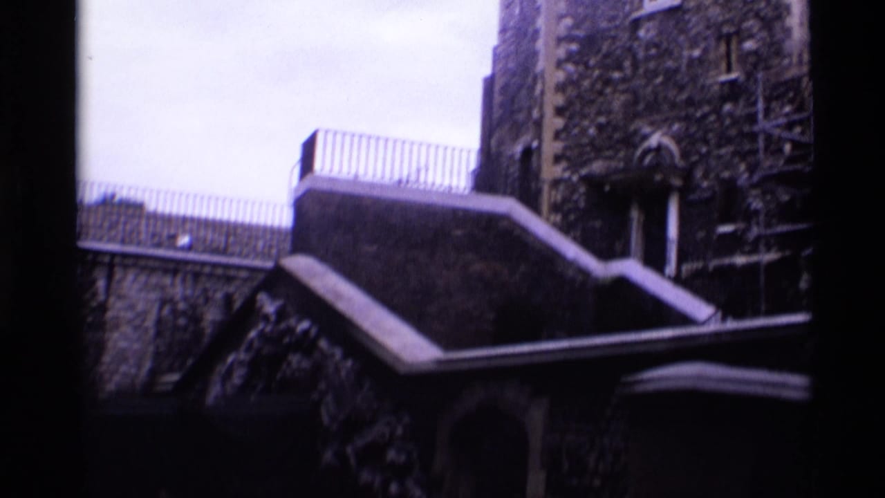 1969 London 8mm frame showing a shadowed stone building exterior with steps, railing, arched doorway, and climbing vegetation.