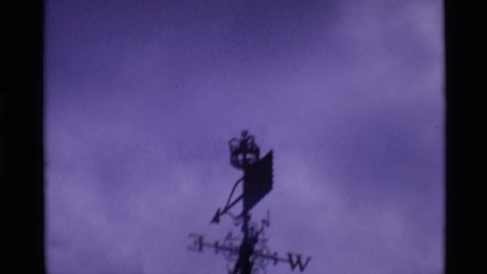 Purple-tinted 1969 London frame showing a dark silhouetted weathervane or roof ornament against clouded sky.