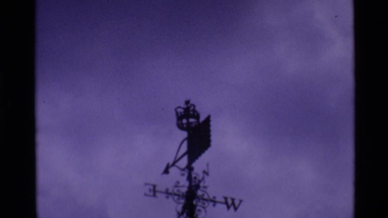 A silhouetted weather vane and roofline appear against a purple sky in 1969 London home-movie footage.
