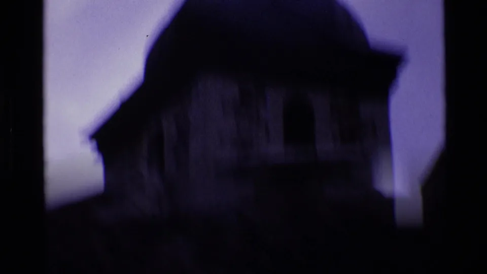 A shadowed historic roofline appears in soft focus against the blue-purple sky in London footage from 1969.