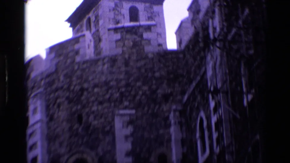 A stone tower with arched windows and textured masonry is filmed from below in 1969 London home-movie footage.