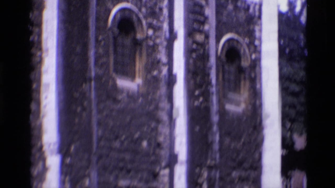 1969 London 8mm frame showing medieval stonework, arched windows, and a shadowed passage at a historic site.