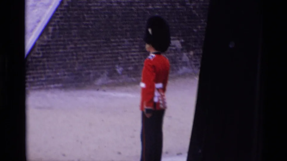 1969 London frame with a ceremonial guard in red uniform and tall black hat seen from a visitor viewpoint.