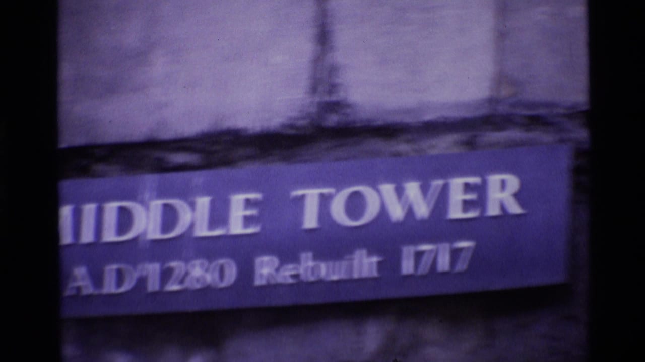 Close handheld 1969 London view of a blue Middle Tower sign on weathered stone, with the text partly blurred.
