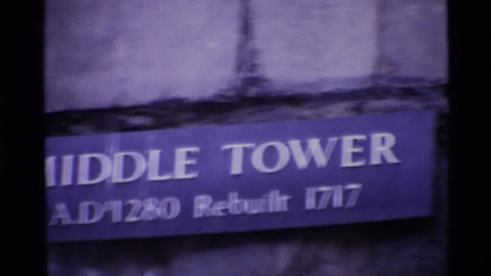 Close handheld 1969 London view of a blue Middle Tower sign on weathered stone, with the text partly blurred.