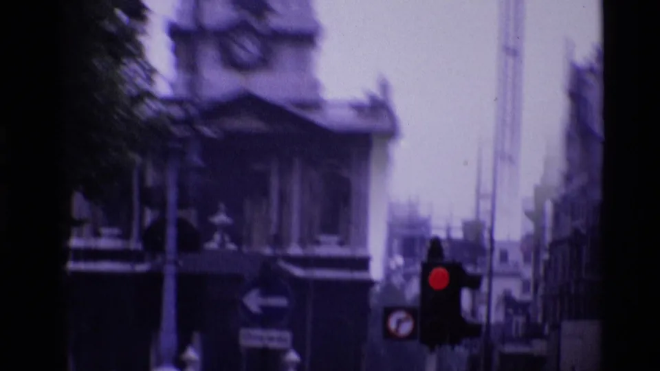 Soft 1969 London street frame with a church facade in the background and a red traffic light in front.