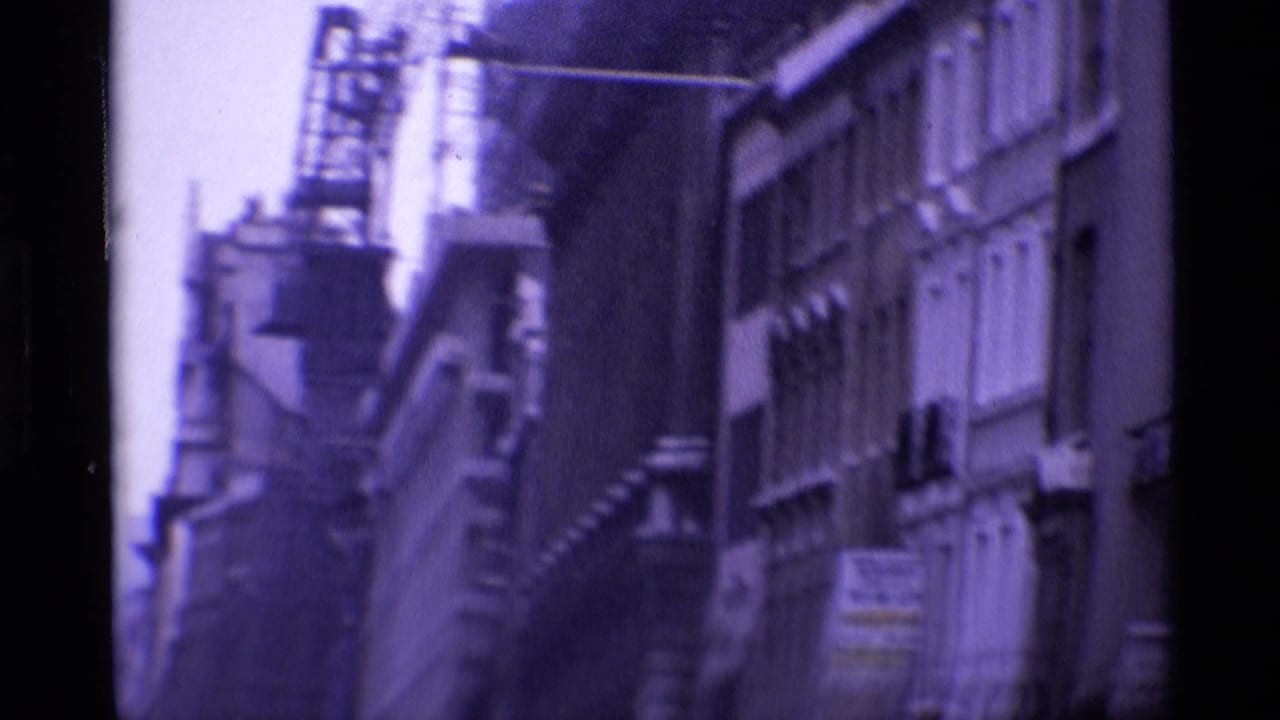 Narrow street view with building facades and a construction crane above the roofline.