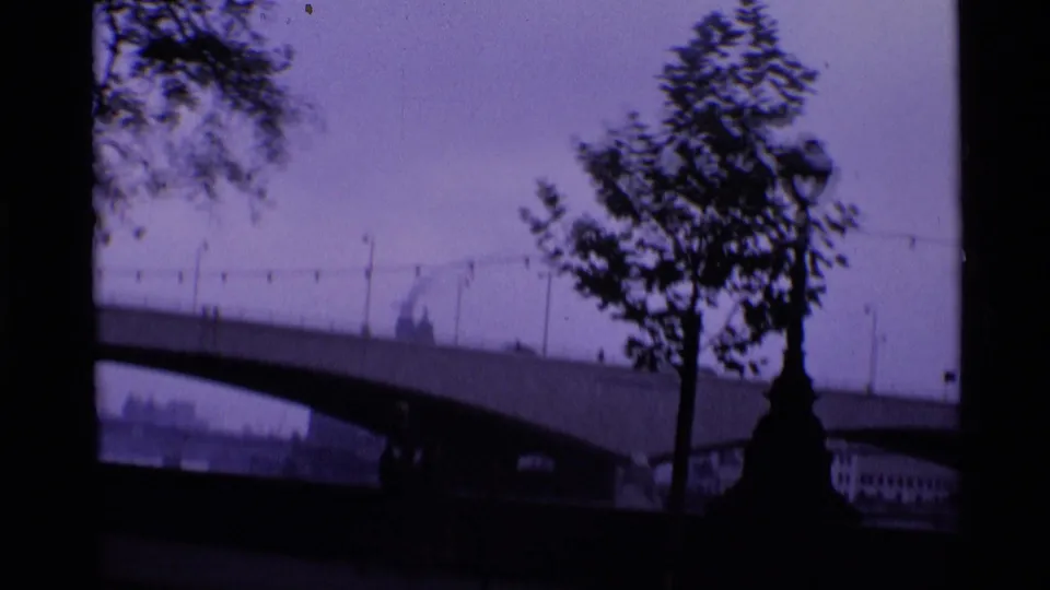 Purple-tinted 1969 London view of an arched bridge with small distant figures and trees in silhouette.
